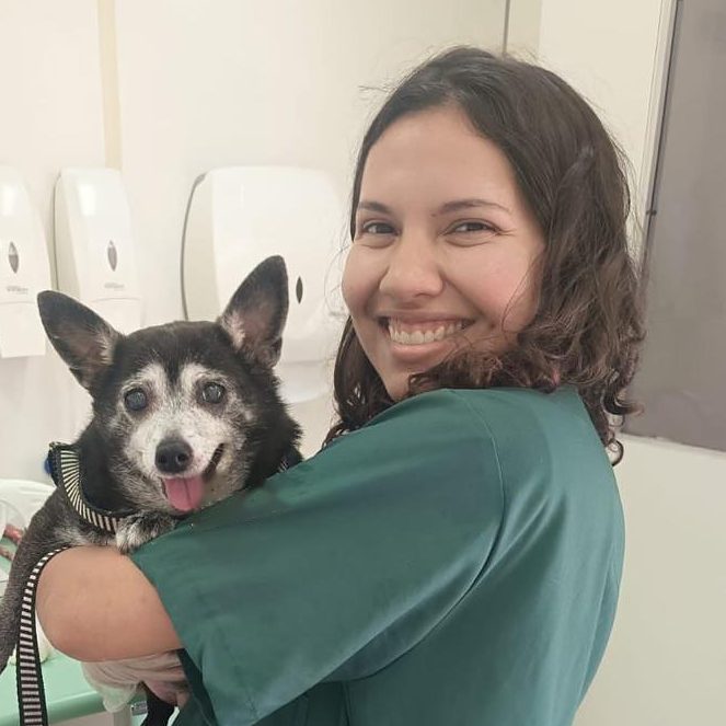 Bianca Barbara sorrindo com um cão idoso de focinho grisalho no colo