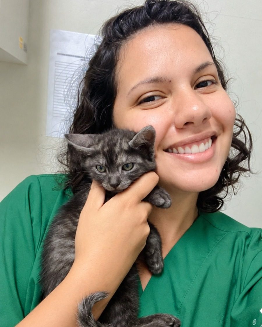 Bianca Barbara sorrindo com um gatinho cinza encostado no rosto