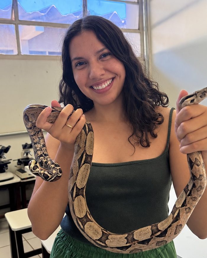 Bianca Barbara segurando uma jiboia em ambiente fechado
