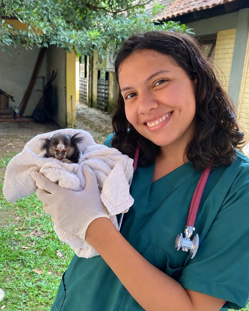 Bianca Barbara ao ar livre, segurando um sagui enrolado em uma toalha